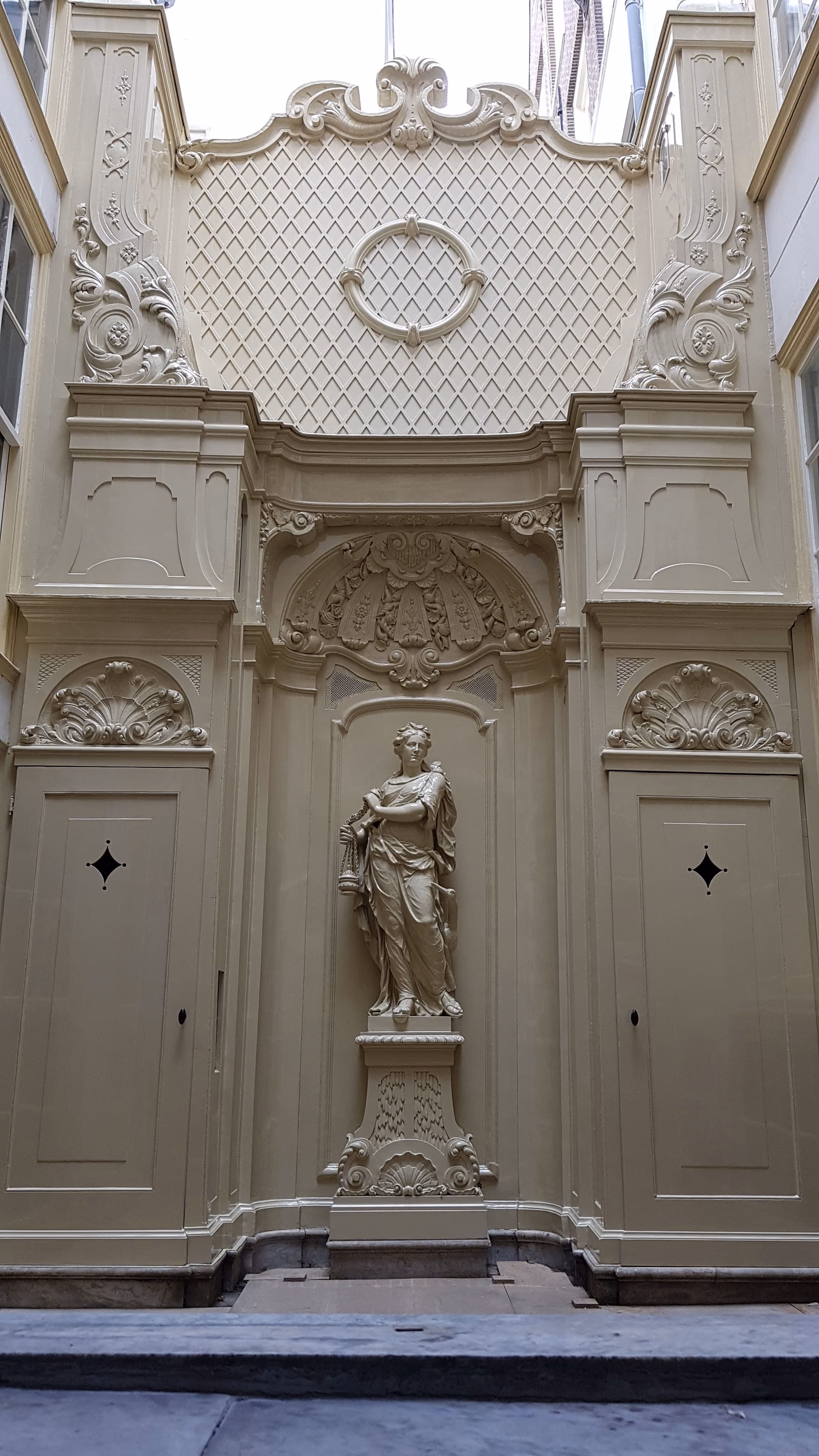 Rijk versierde, klassiek geschilderde gevel met stucwerk en beeld